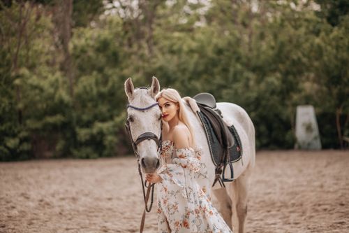 Free A woman in floral dress with a horse outdoors, showcasing equestrian elegance. Stock Photo