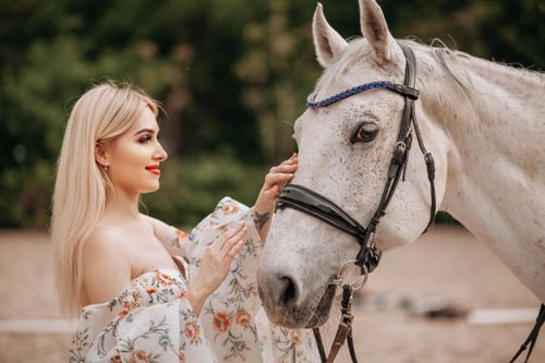 Free A young woman interacting with a white horse, showcasing elegance in an outdoor setting. Stock Photo