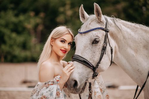 Free A graceful woman poses with a beautiful white horse outdoors, embodying elegance and connection. Stock Photo