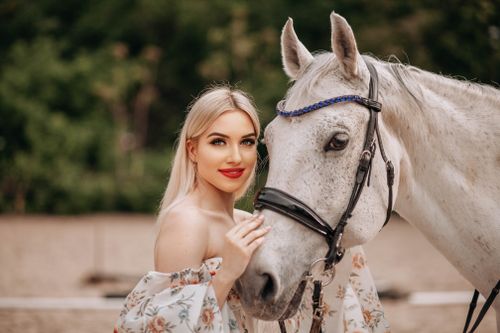 Free Beautiful woman posing with a white horse in a scenic outdoor setting. Stock Photo