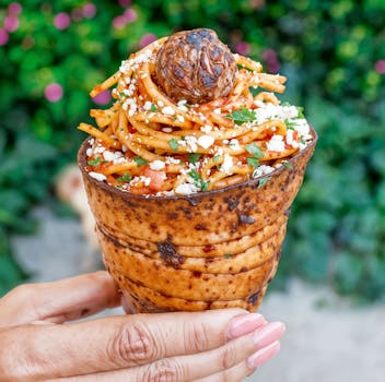 Delicious plant-based spaghetti served in a savory cone with vegan cheese and fresh herbs.