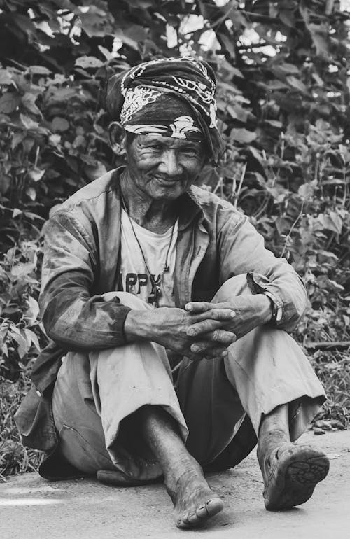 Grayscale Photography Of Old Man Sitting Near Plants