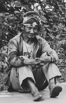一位尼泊尔老人坐在户外，黑白肖像展现出坚韧