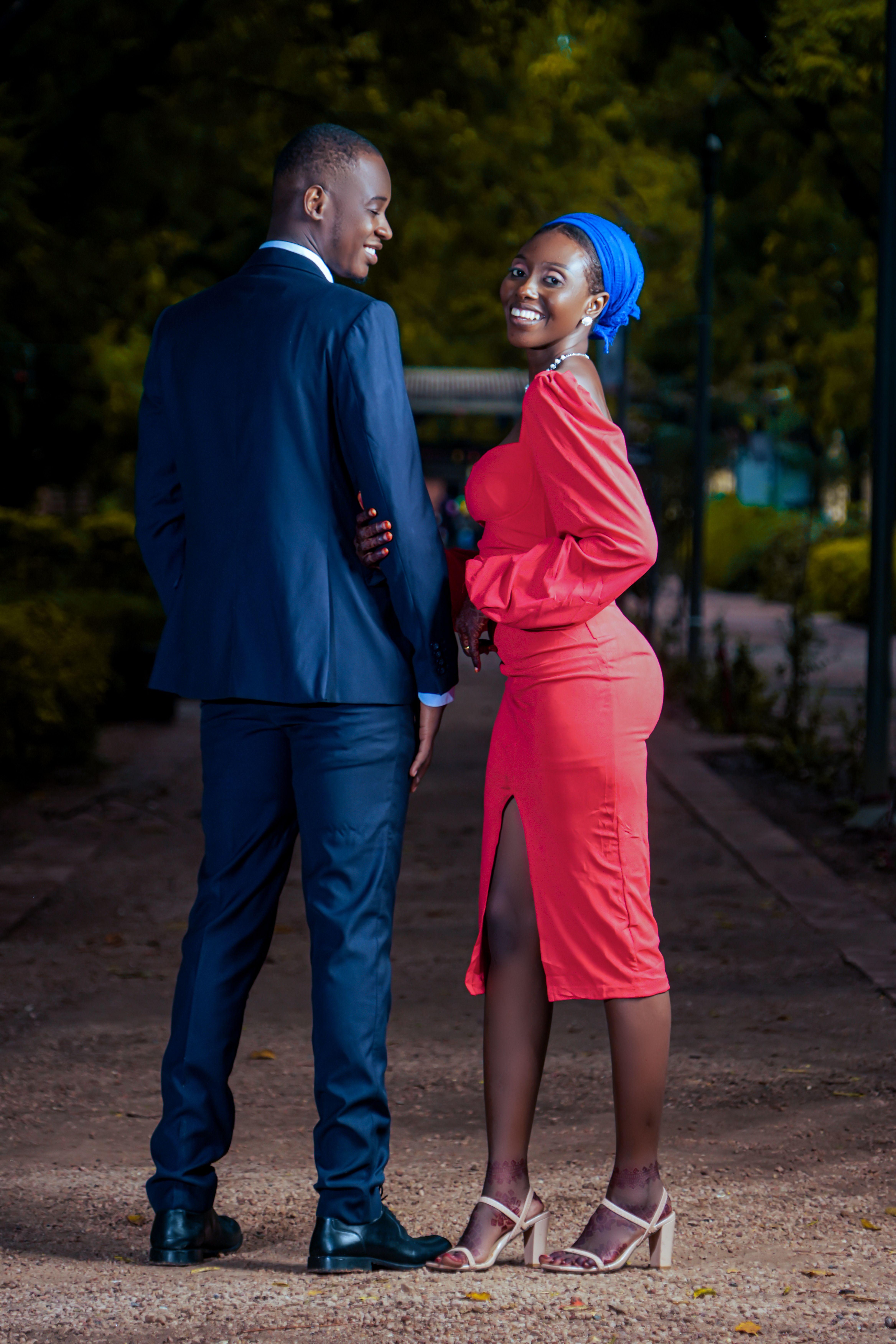 Couple enjoying a stylish evening in a park, showcasing fashion and smiles.