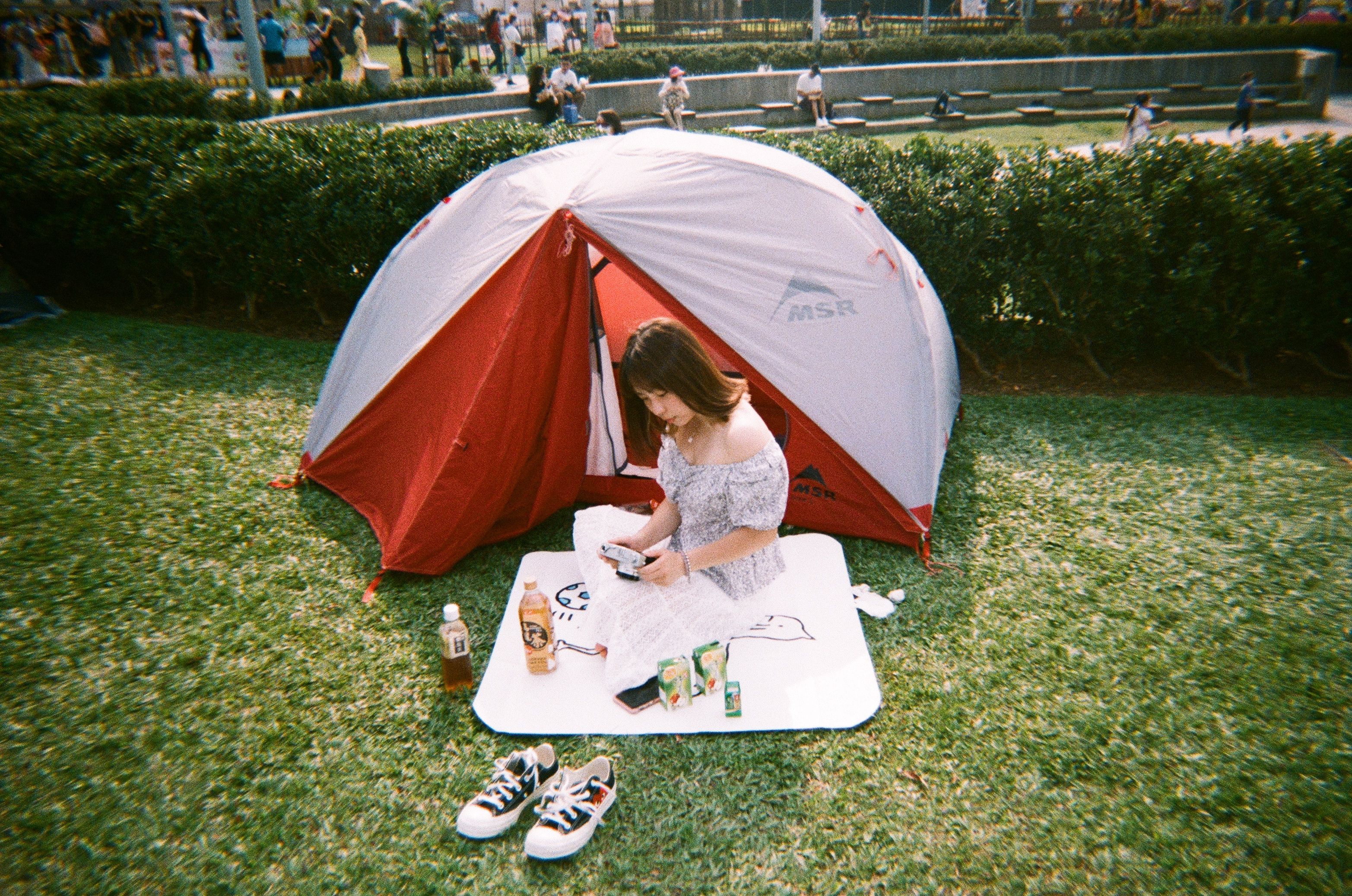 Jovem preparando um lanche ao ar livre sob uma tenda em um parque, em um momento de lazer ao ar livre.