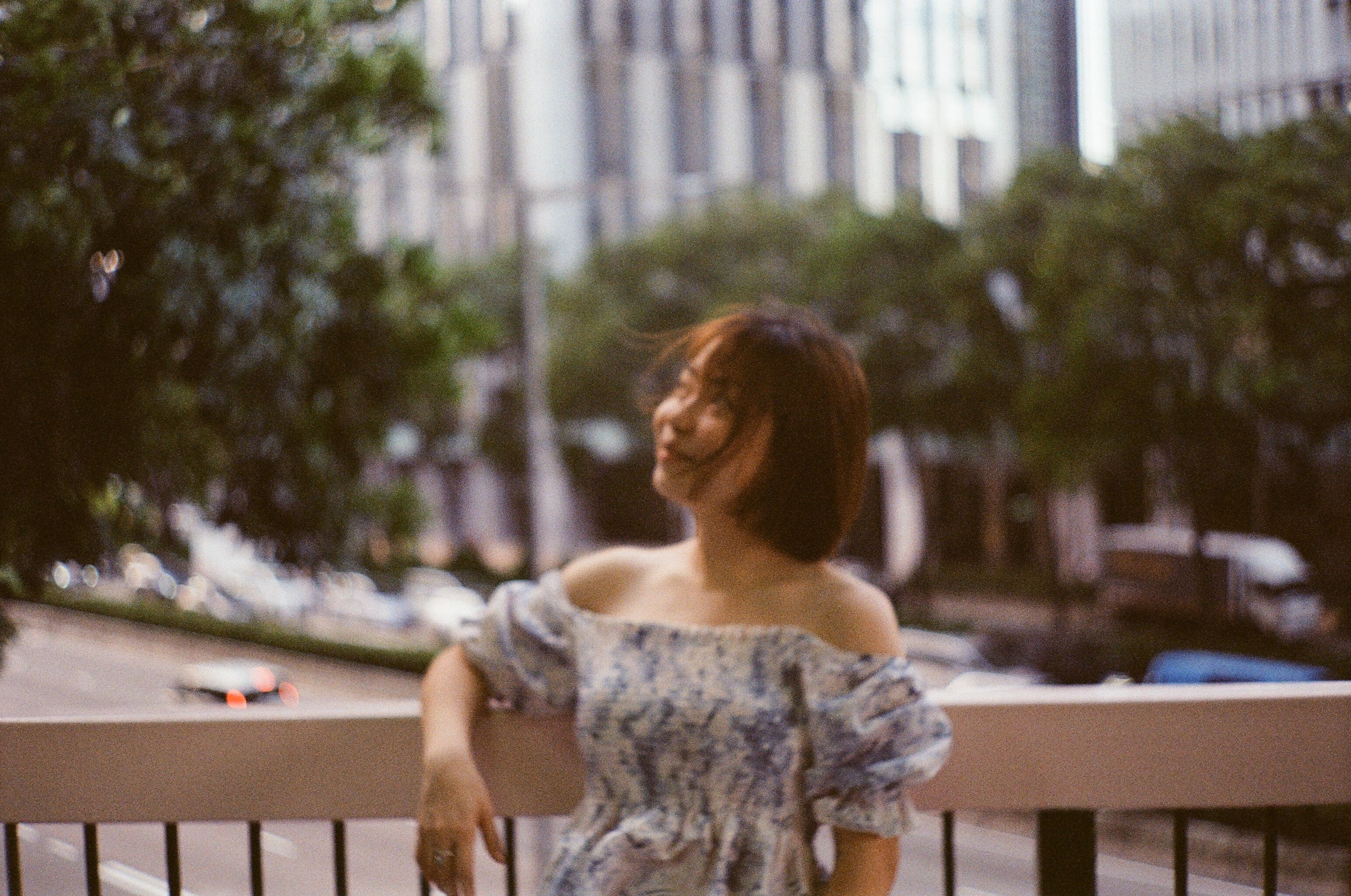 A woman in a dress leaning against a railing · Free Stock Photo
