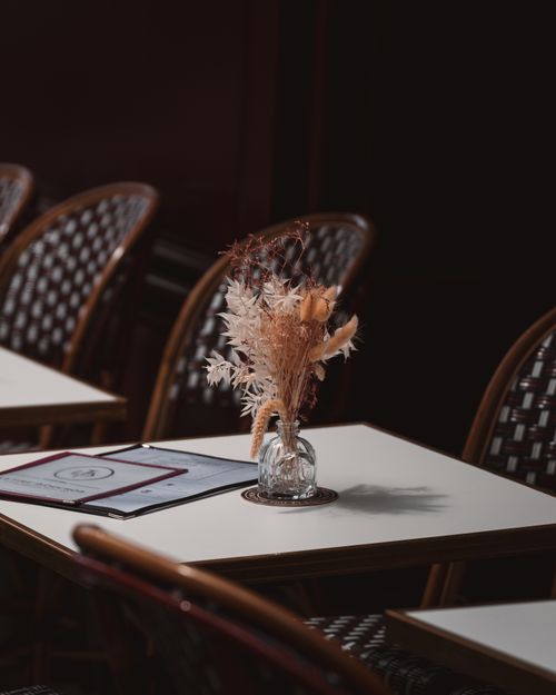 Free Charming Parisian café featuring wicker chairs and elegant table decor creating a cozy ambiance. Stock Photo