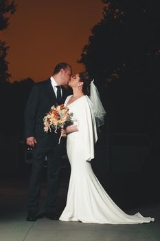 Romantic portrait of a bride and groom kissing at sunset, celebrating their love.
