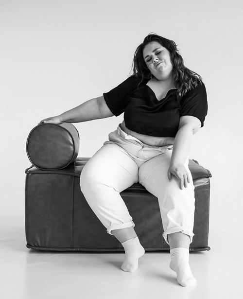 Free Black and white portrait of a woman sitting casually on a modern leather chair in a studio. Stock Photo