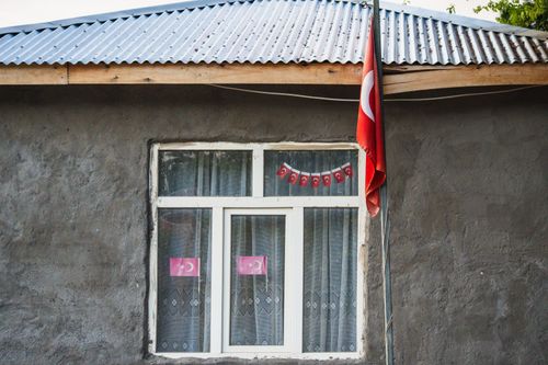 Free A rustic house in Kuşhane, Türkiye featuring a Turkish flag and traditional architecture. Stock Photo