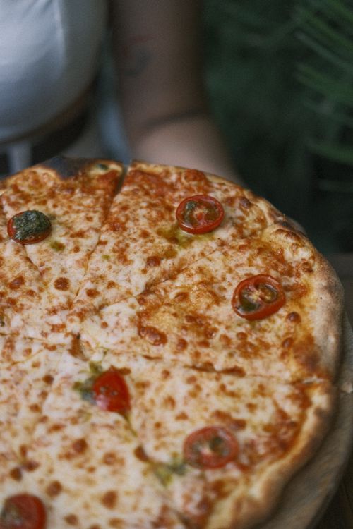 Free Delightful cheese pizza topped with cherry tomatoes, showcasing a savory meal option. Stock Photo