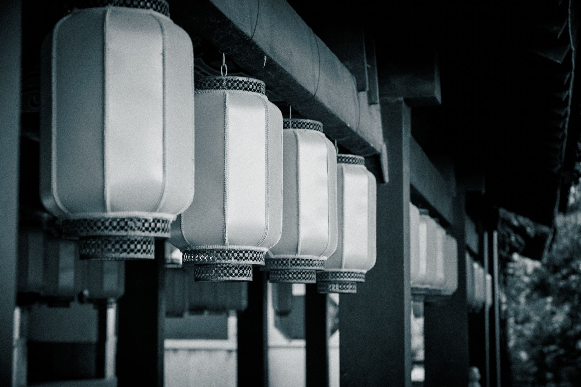 Row of vintage lanterns hanging in a serene outdoor setting, evoking a retro charm.