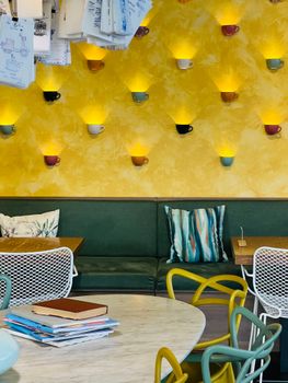 A lively cafe interior featuring a unique wall of illuminated cups and modern furniture.