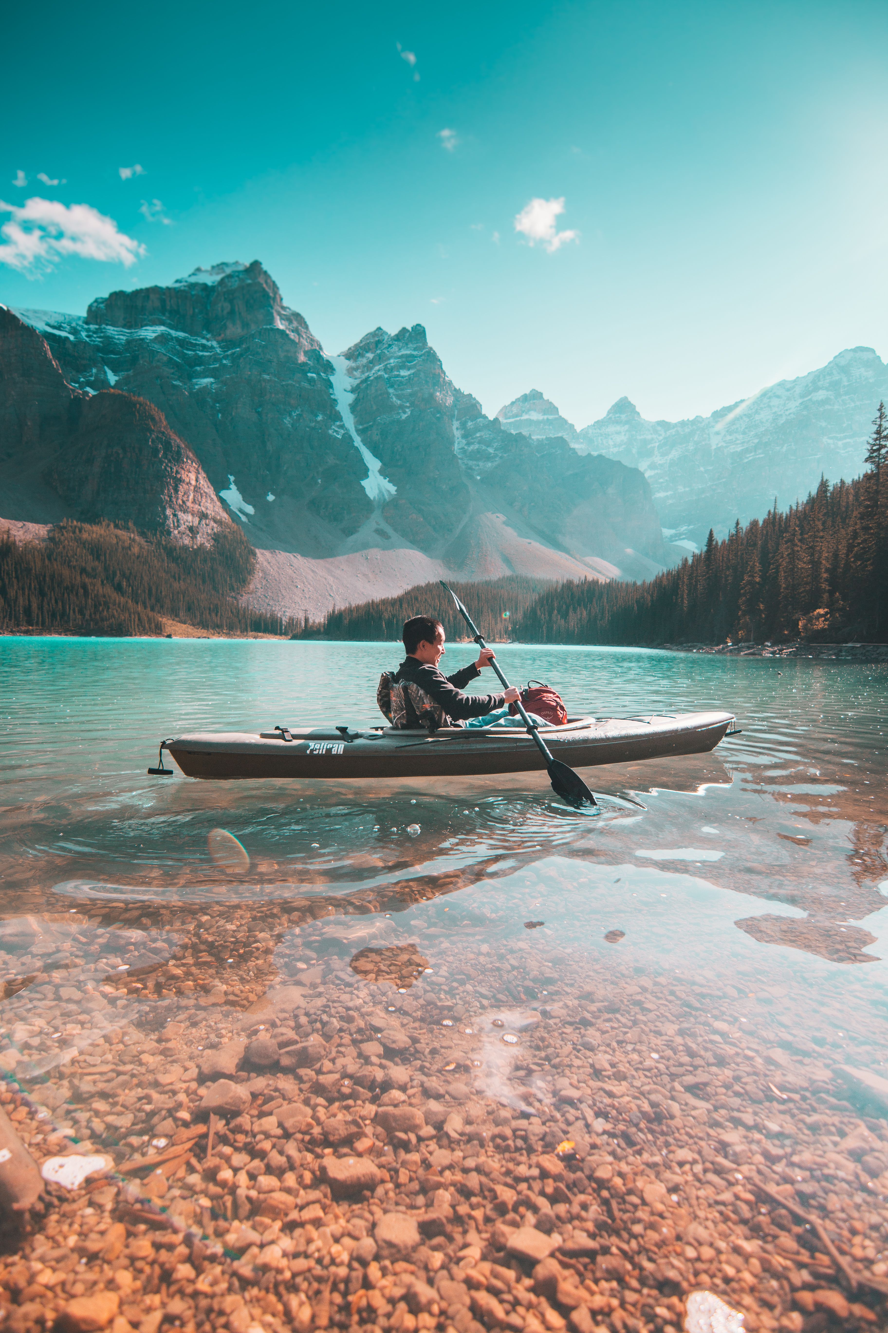 A kayaker crossing still water beneath the peaks at dawn
