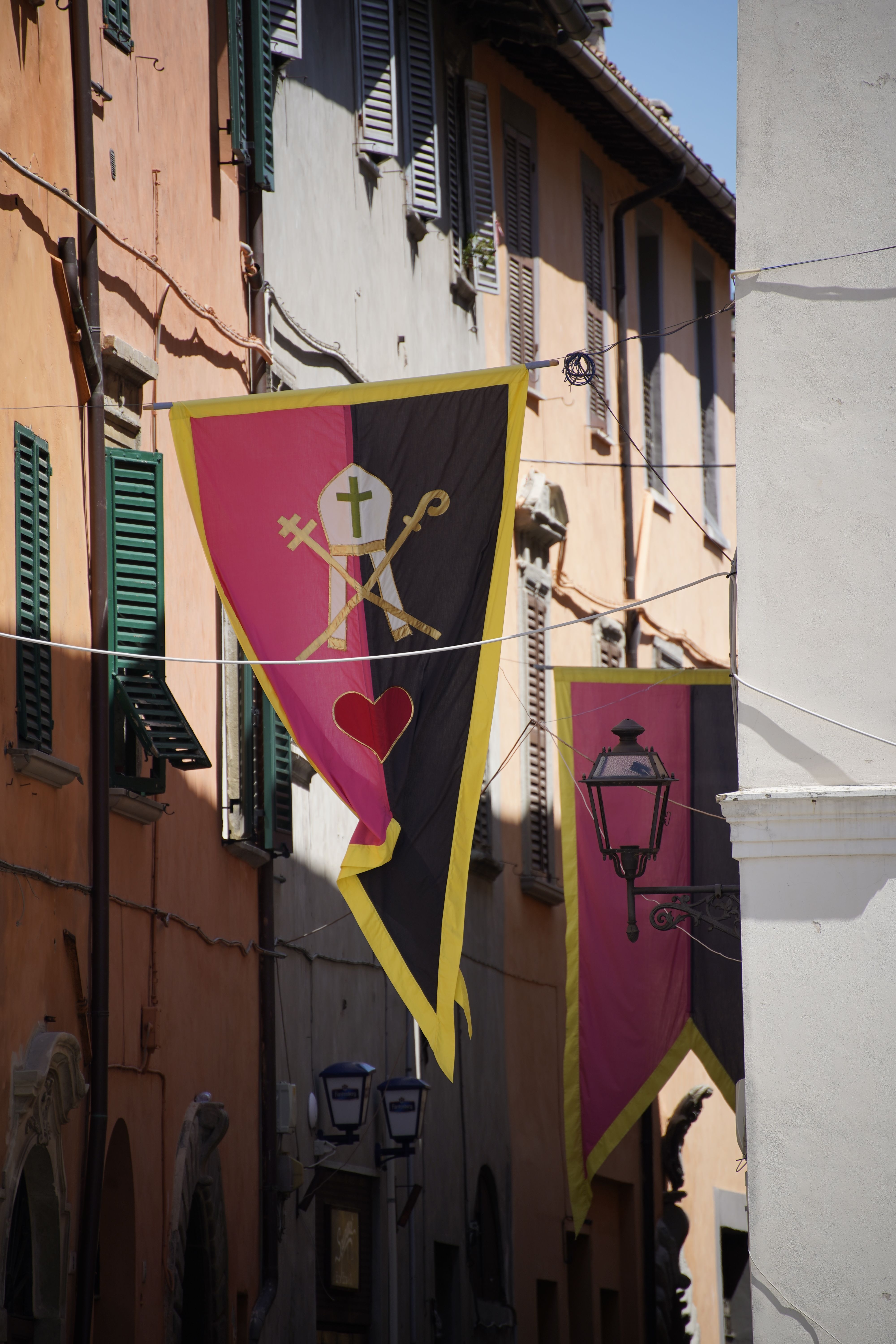 Charming Cagli street view with traditional Italian banners during festive season.