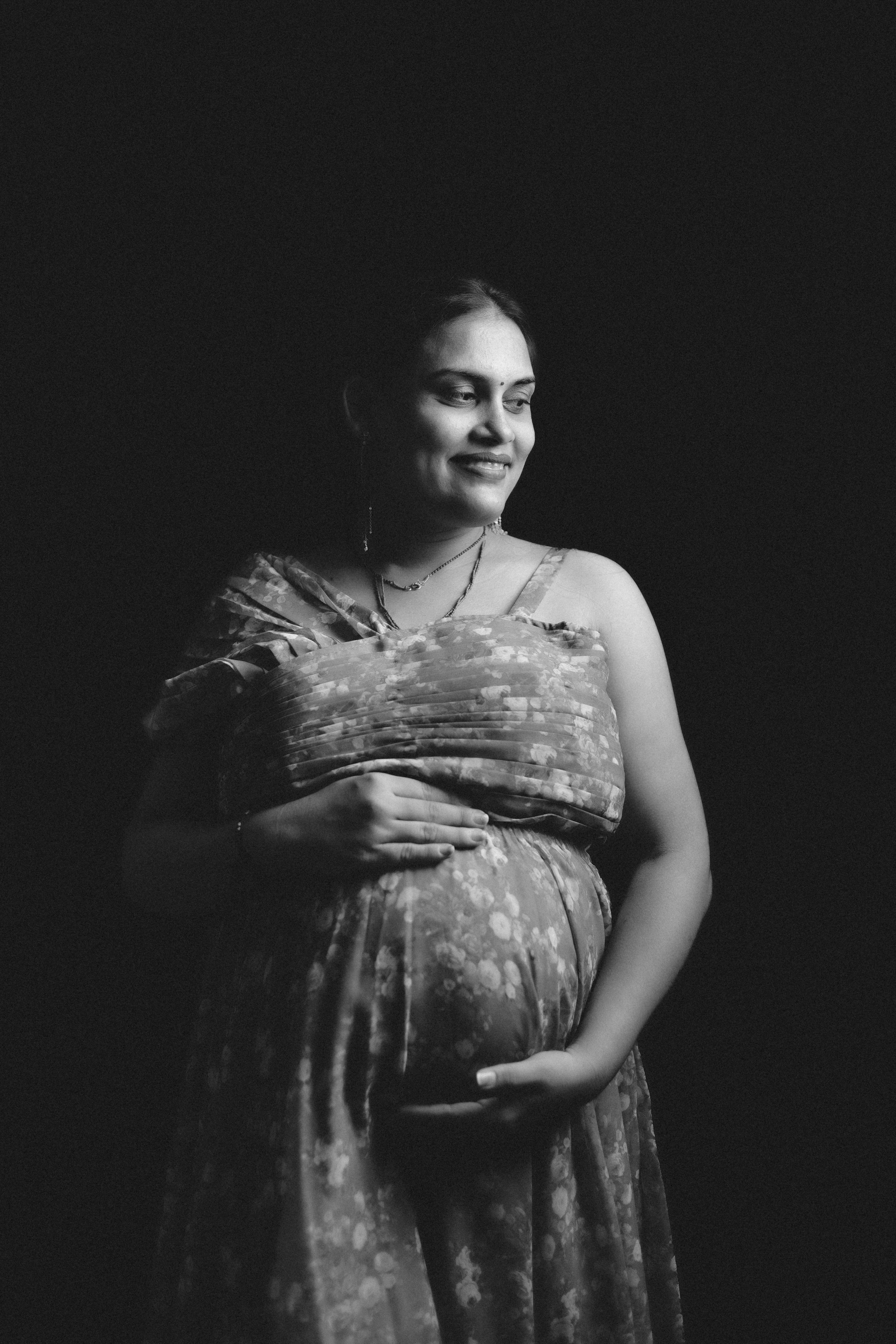 Fotomural Retrato elegante en blanco y negro de una mujer embarazada sonriendo en un entorno de estudio.