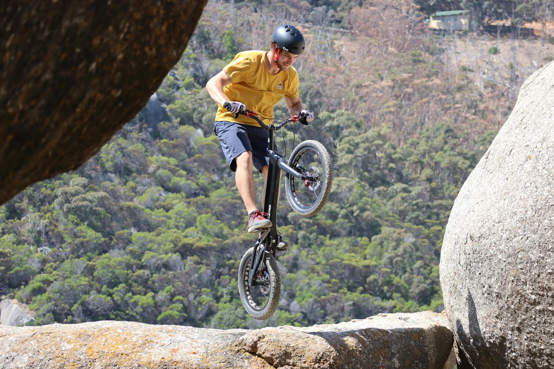 Energetic mountain biker performing a jump between rocks, showcasing extreme sportsmanship.