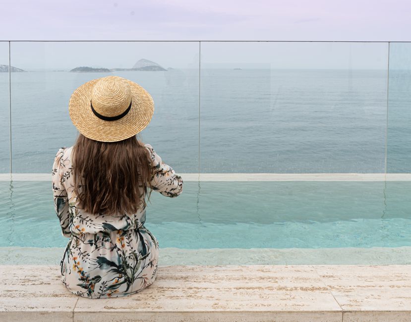 Mulher relaxando em piscina infinita de hotel de luxo, destacando experiências imersivas.