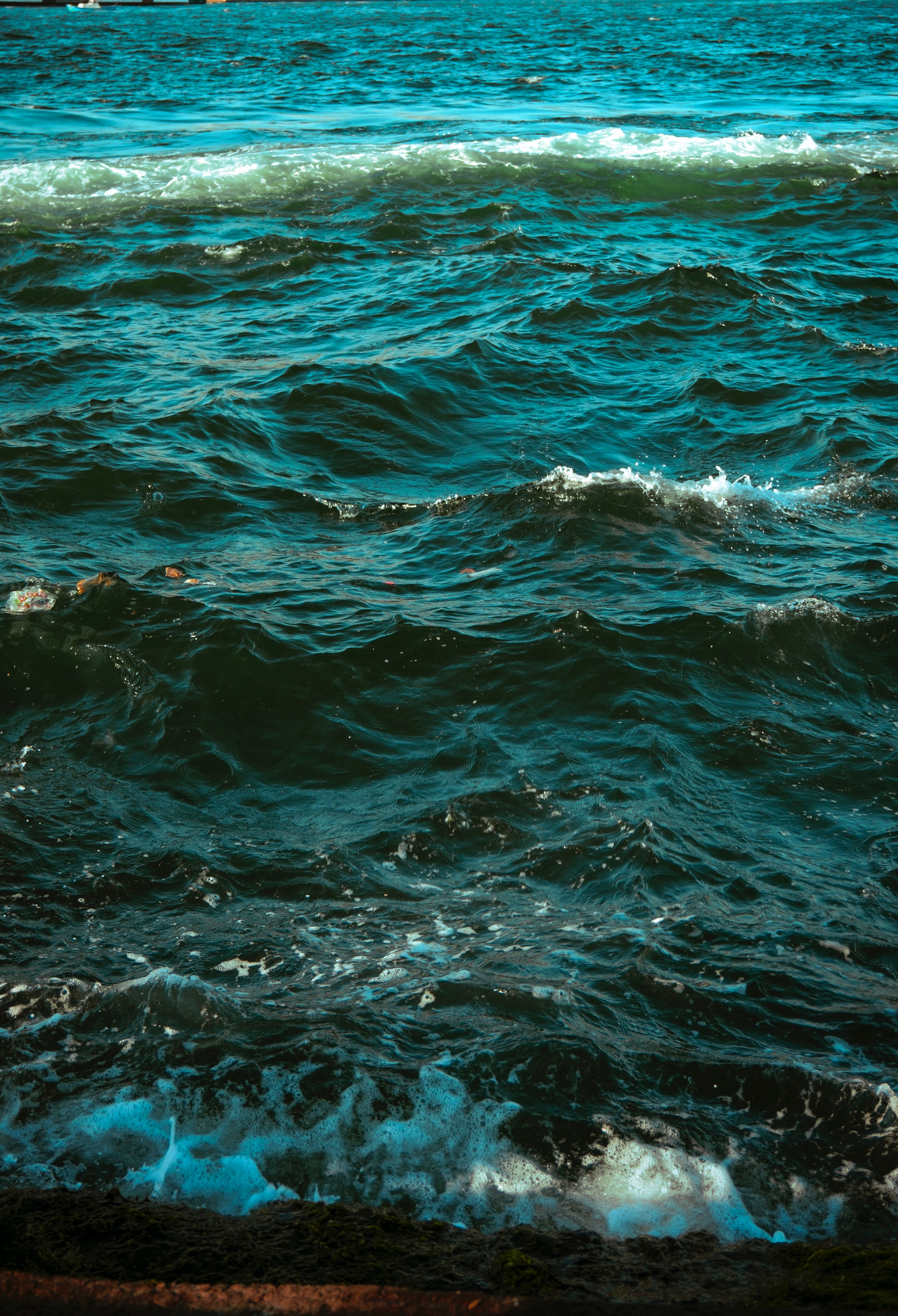 Captivating view of vibrant turquoise ocean waves crashing along the shoreline, reflecting sunlight.