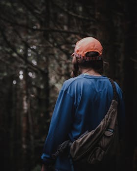 一名女子头戴帽子、身背背包，探索着茂密幽暗的森林，充满了户外冒险的氛围