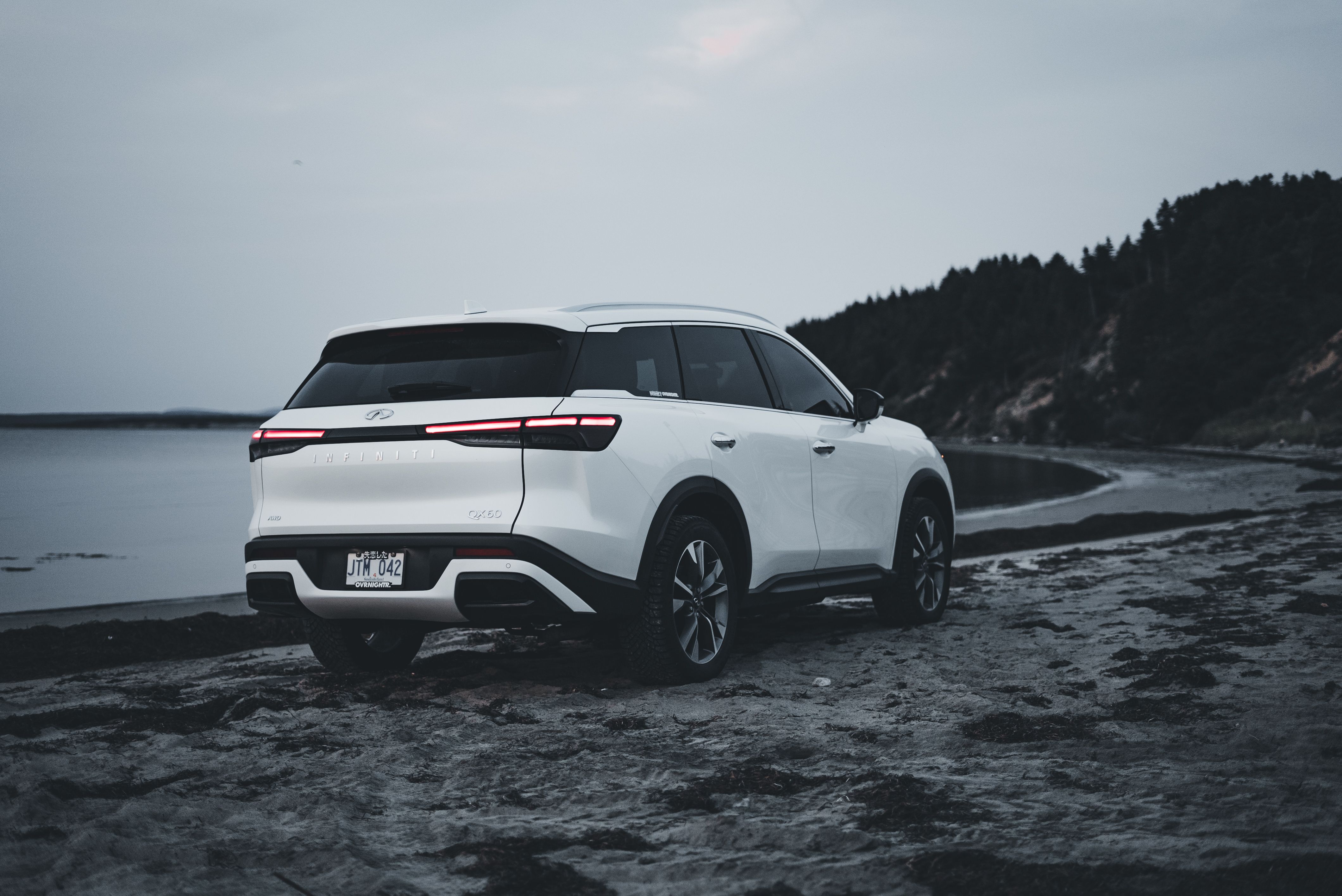 White SUV parked on a scenic beach at dusk