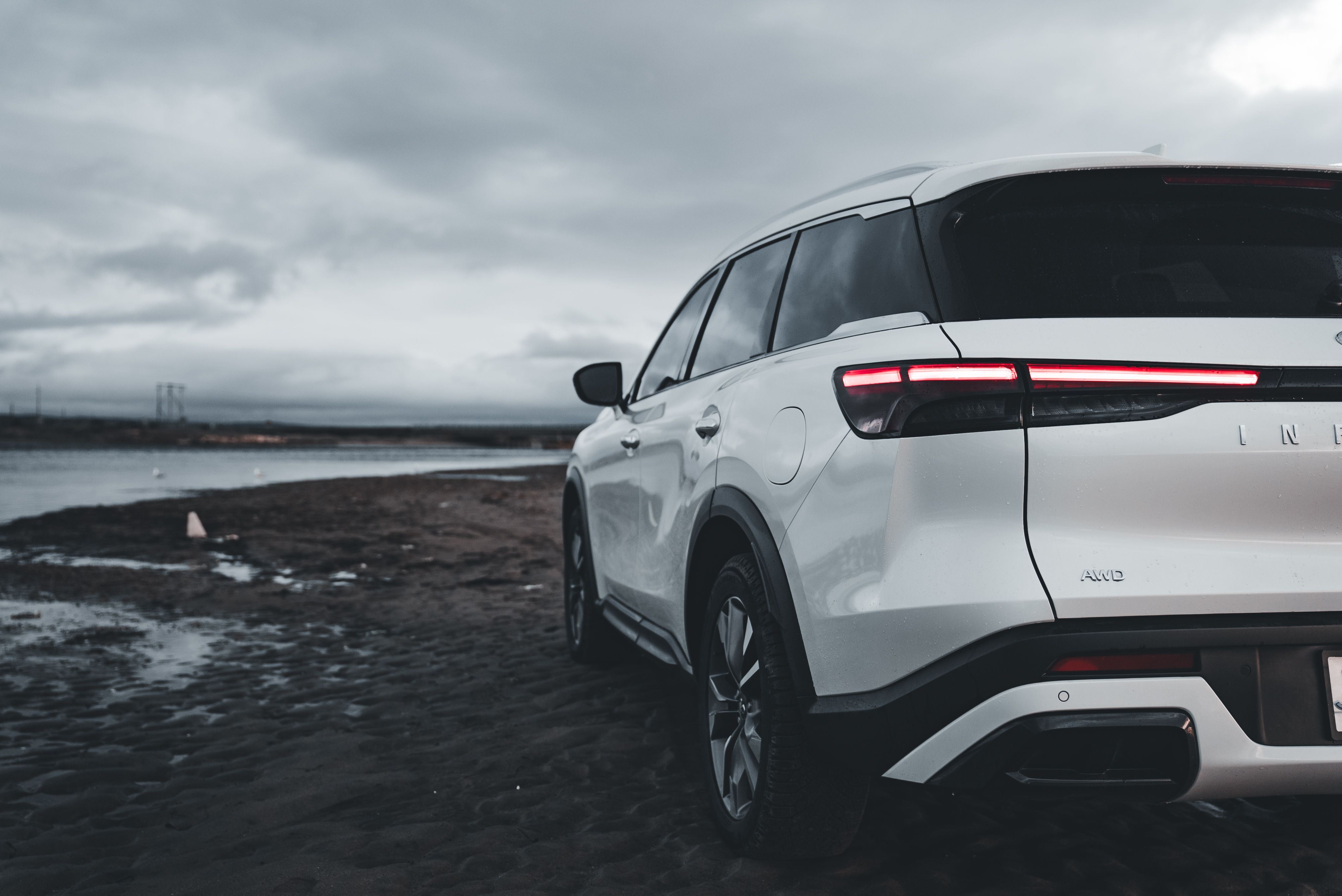 The rear end of a white suv parked on the beach · Free Stock Photo