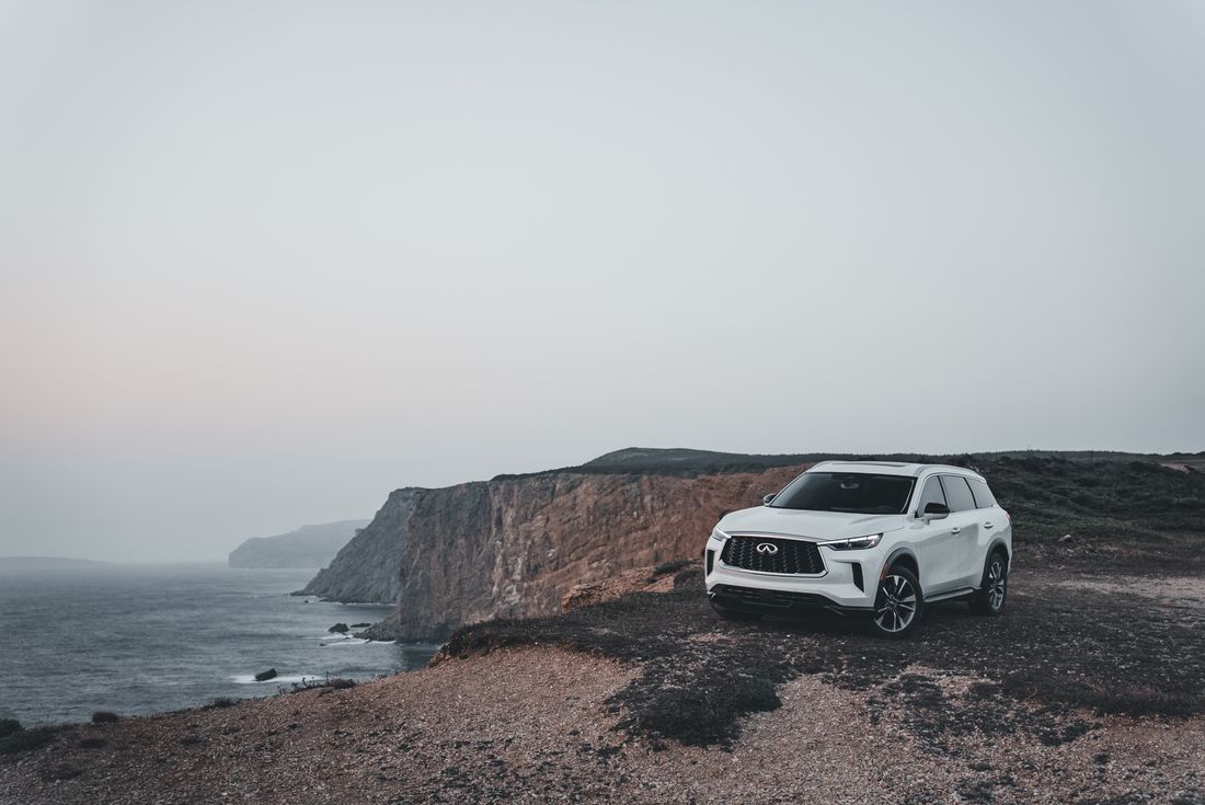 A stylish SUV parked beside majestic coastal cliffs at dusk