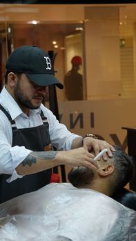 Barber performing a professional haircut and shave indoors. Adult men engaged in a traditional grooming session.