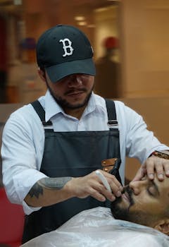 Professional barber carefully shaping beard in a modern barbershop setting.