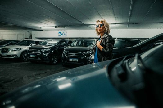 Fashionable woman wearing sunglasses in a dimly lit parking garage in Buenos Aires.