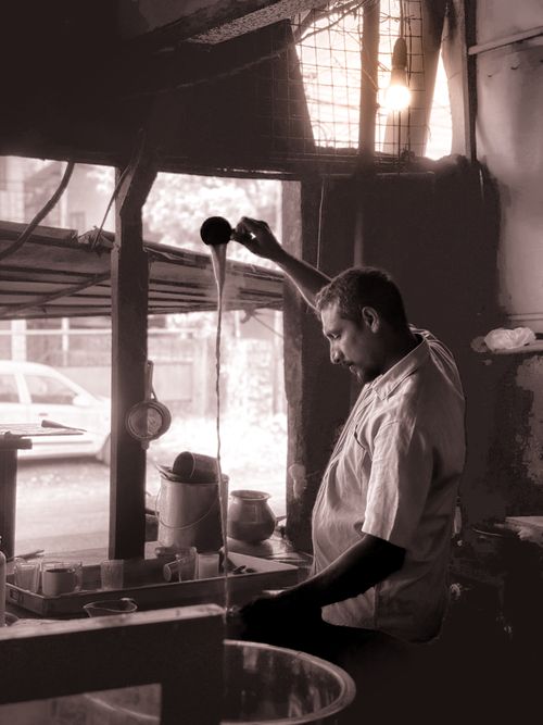 Free An artisan skillfully pours tea inside a vintage-styled tea house. Captured in muted tones. Stock Photo