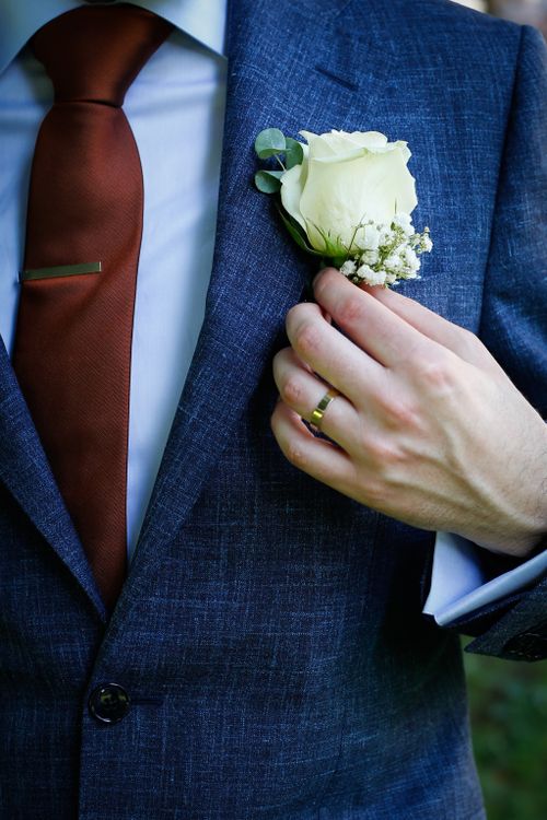 Free Groom adjusting white rose boutonniere, showcasing ring and elegant attire on wedding day. Stock Photo