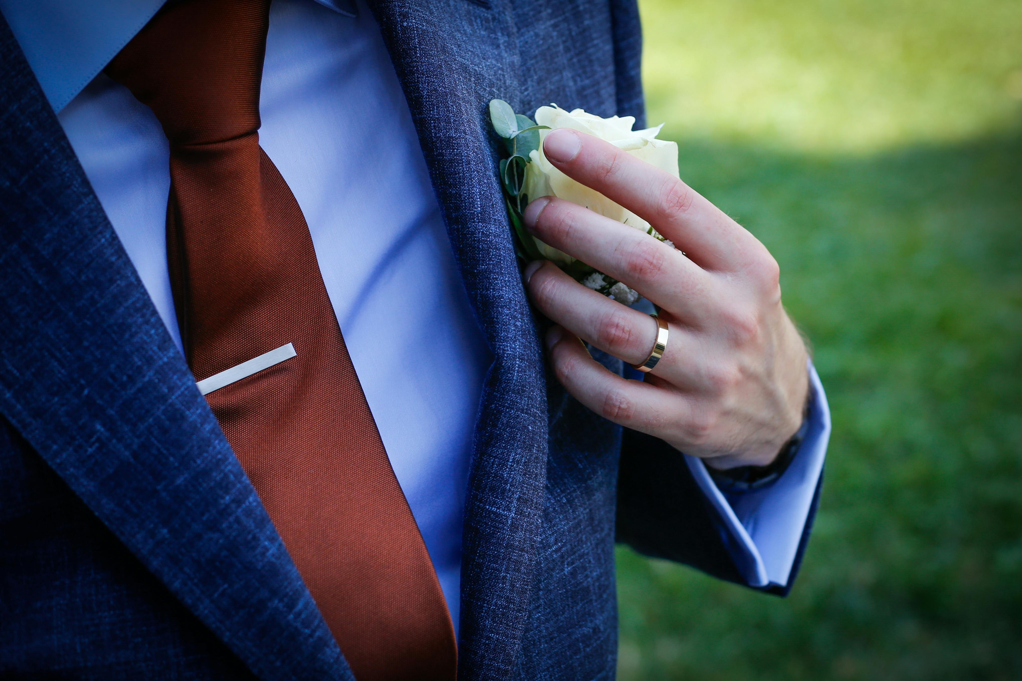 a man in a suit and tie holding a flower