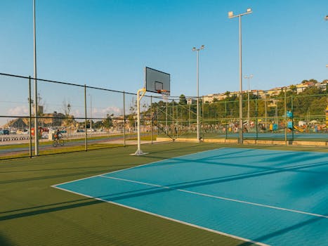 An empty outdoor basketball court with a scenic background under a clear blue sky during the daytime.