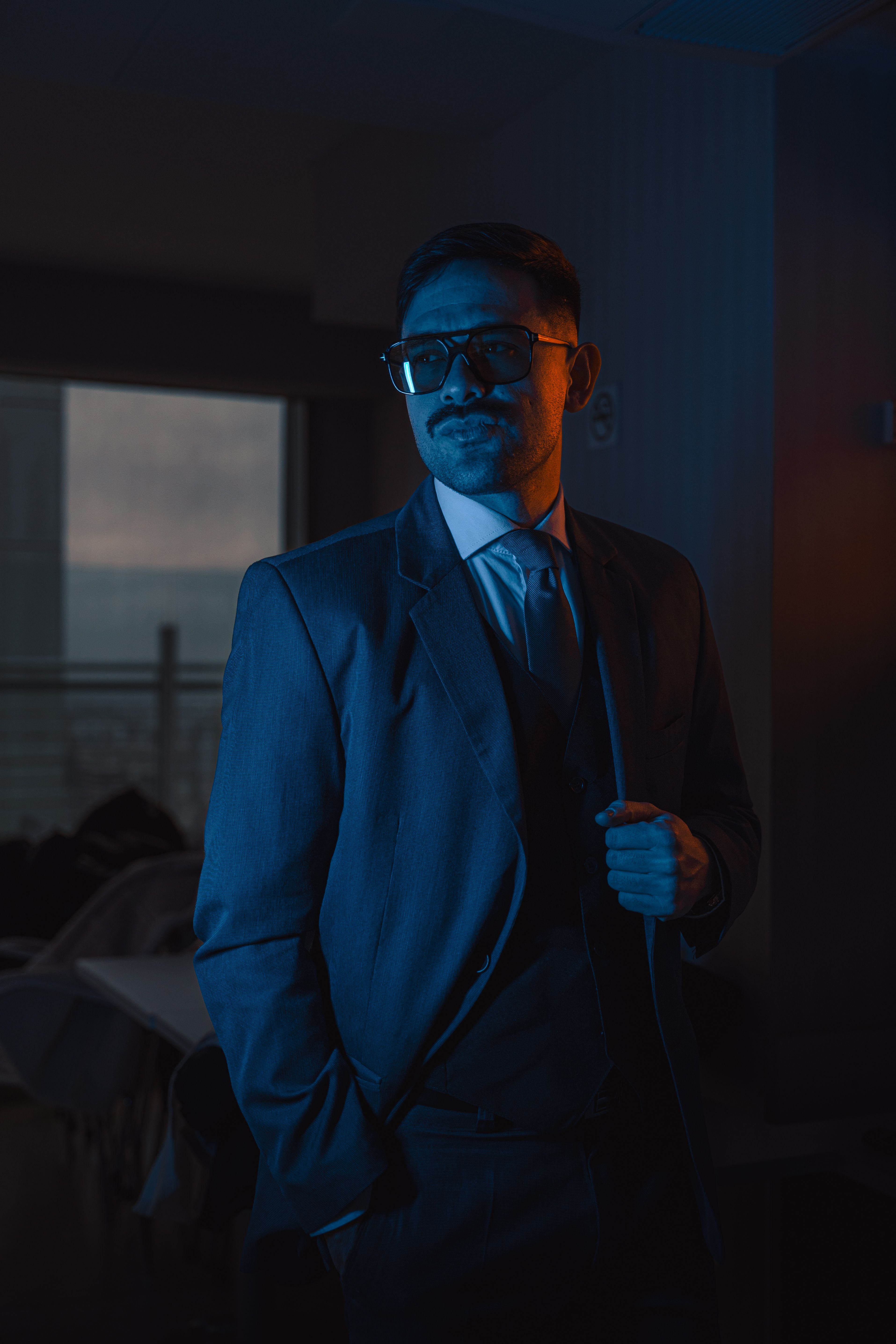 A man in a suit and tie standing in front of a window · Free Stock Photo