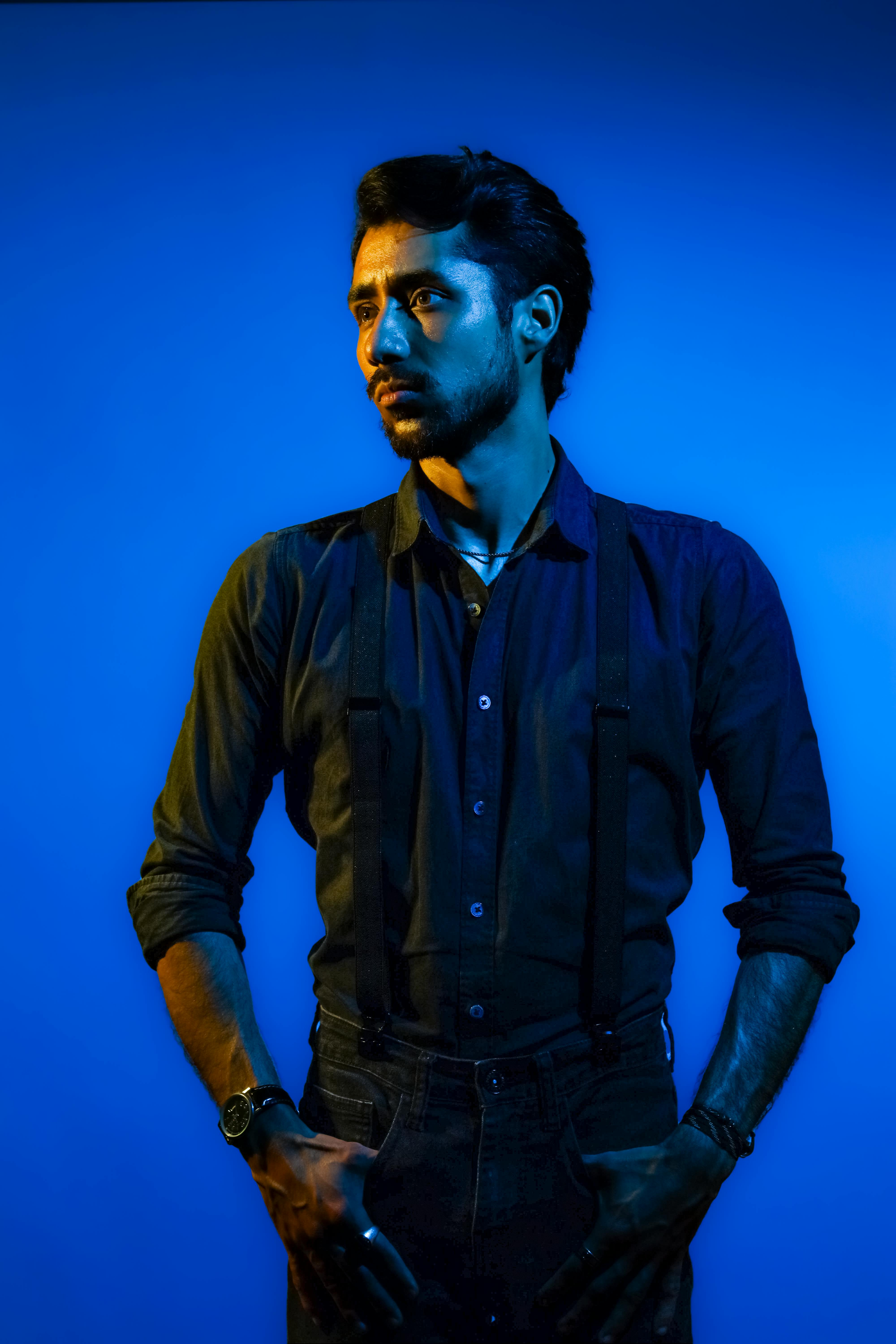 Dramatic portrait of a male musician in a dark blue setting.