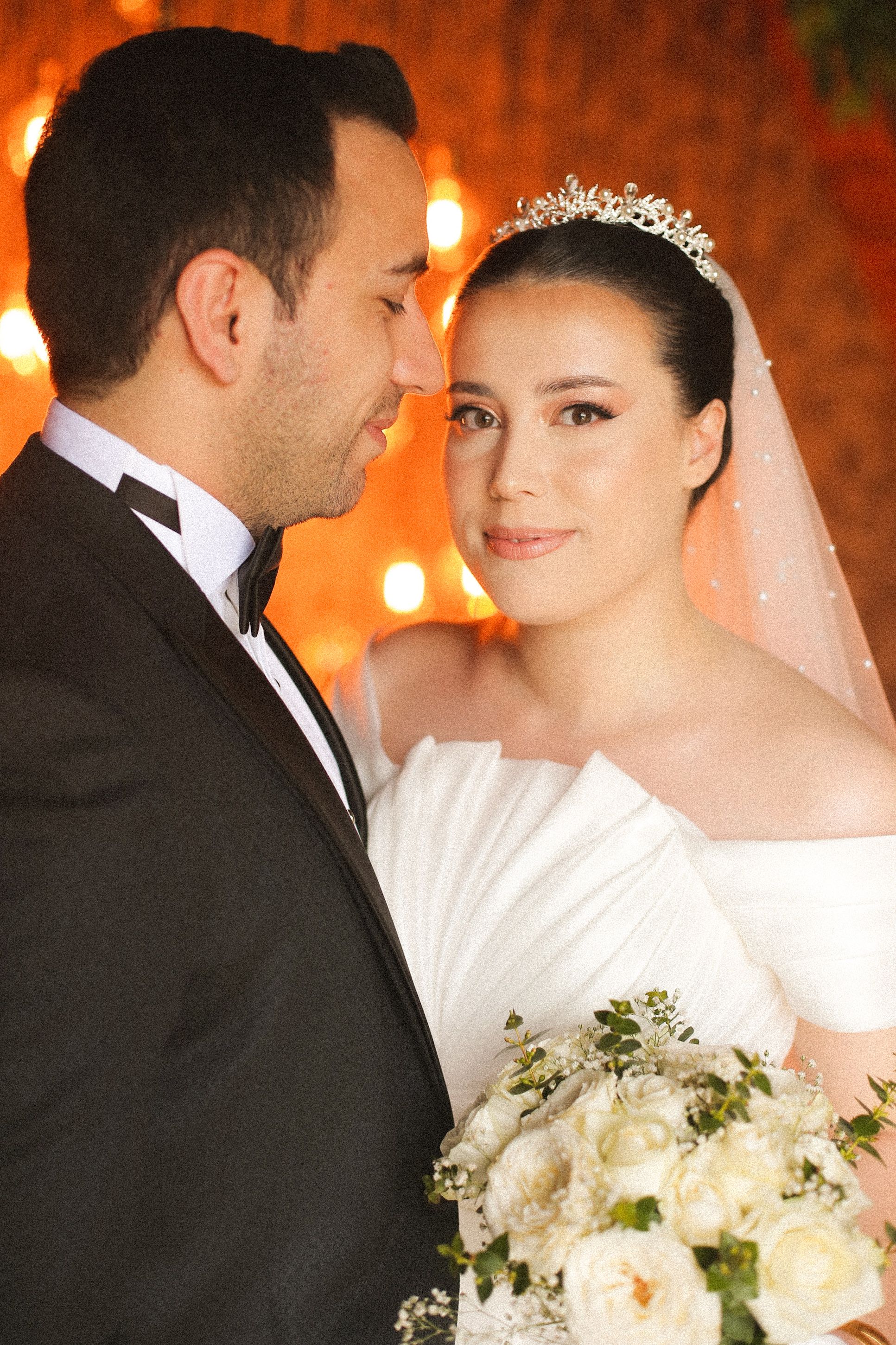 A beautiful couple posing close together, showcasing elegance in their wedding attire.
