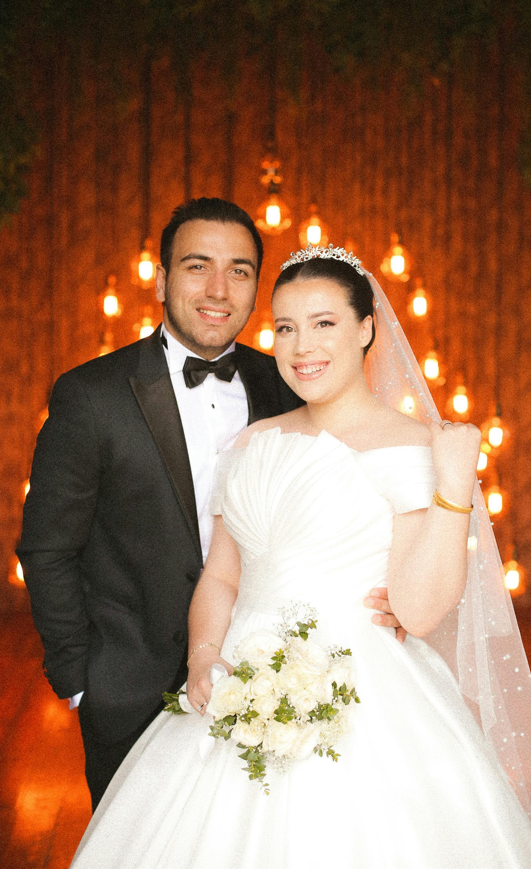 A beautiful wedding photo capturing a joyful couple, elegantly dressed and smiling together indoors.