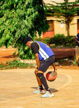 A young man playing basketball outdoors on a sunny day.