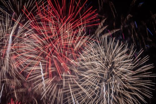 Free Vibrant fireworks illuminate the night sky with red and white bursts, celebrating a festive occasion. Stock Photo