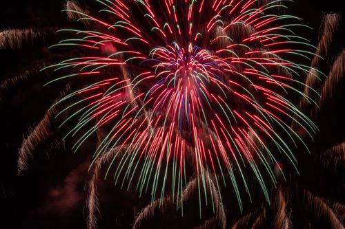 Free Colorful fireworks burst in the night sky over a festive celebration. Stock Photo