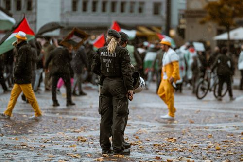 Free Police officers observe a city protest in rainy weather with people holding flags and signs. Stock Photo