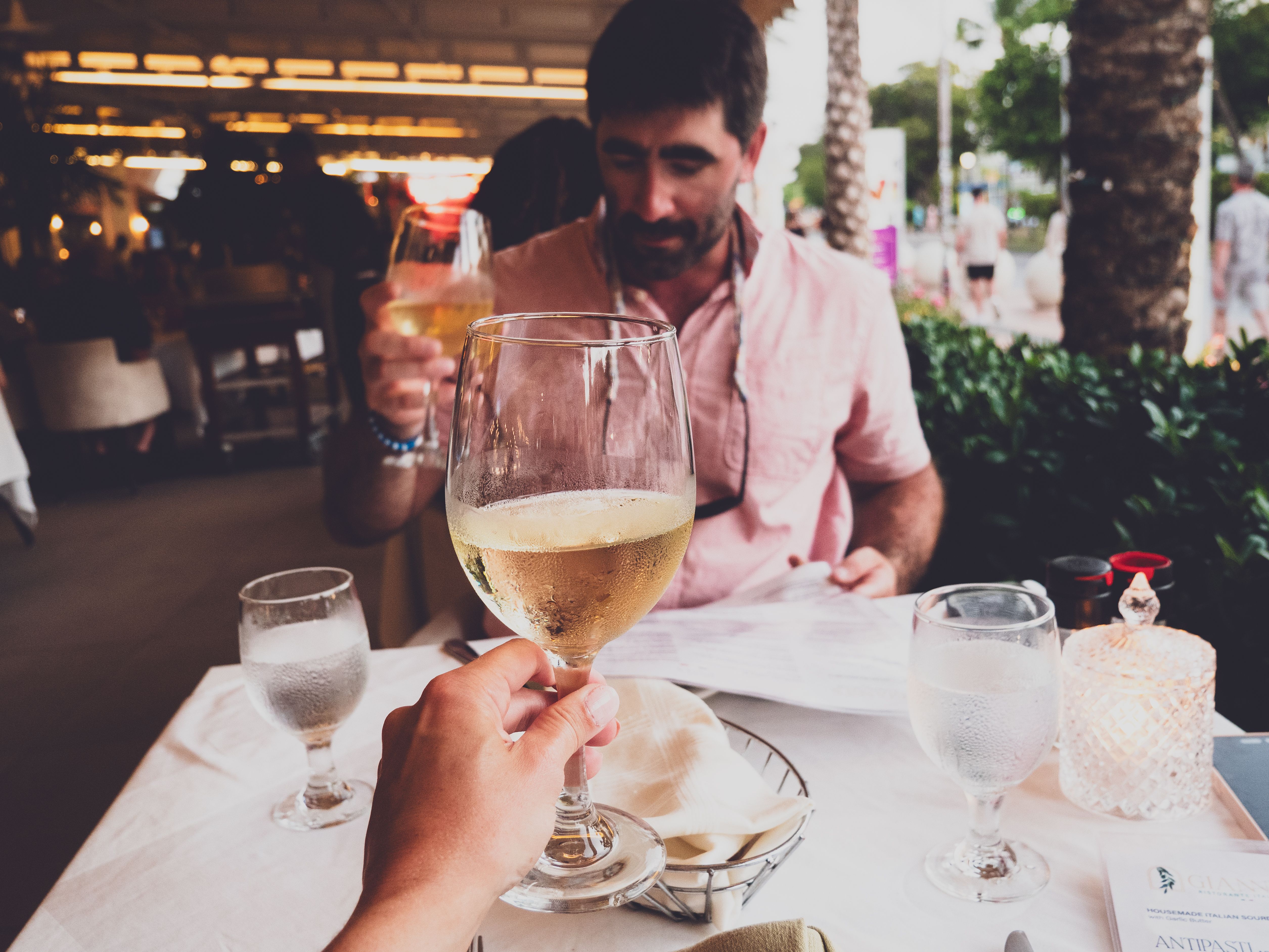 Couple enjoying a romantic dining experience with a toast of white wine, creating a warm and inviting atmosphere. | BocaVibe