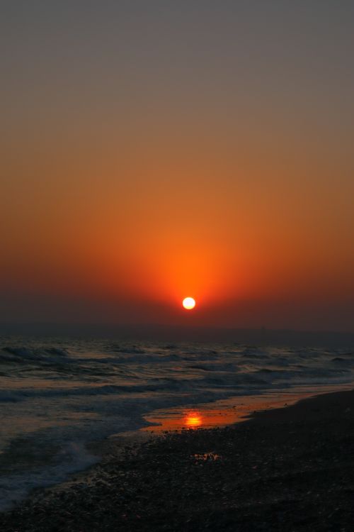 Free Serene beach at sunset with vibrant colors reflecting on water, perfect for travel inspiration. Stock Photo