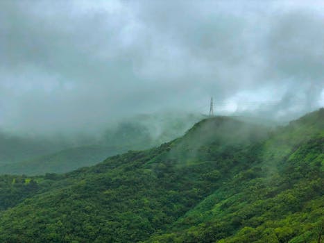 Electric Tower surrounded by cloud with lush green mountain