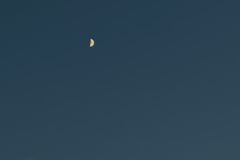 Peaceful evening sky showcasing a crescent moon amidst twilight clouds.