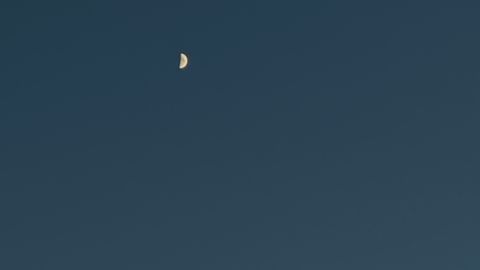 Peaceful evening sky showcasing a crescent moon amidst twilight clouds.