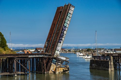 Free Rustic elevated drawbridge over calm water, showcasing urban decay and tranquil harbor scenery. Stock Photo