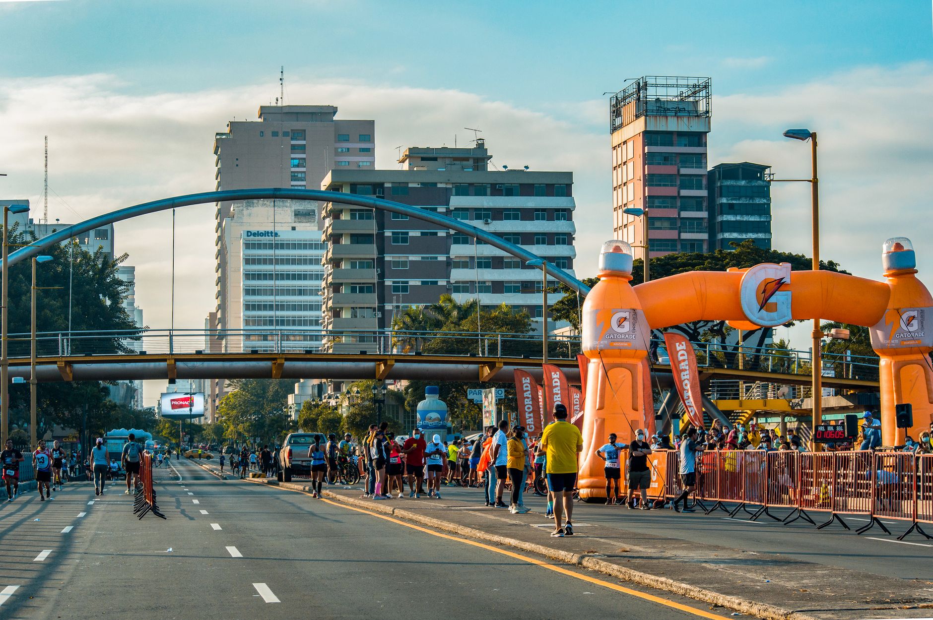 Runners participating in a marathon event amidst a vibrant cityscape under an orange inflatable arch.