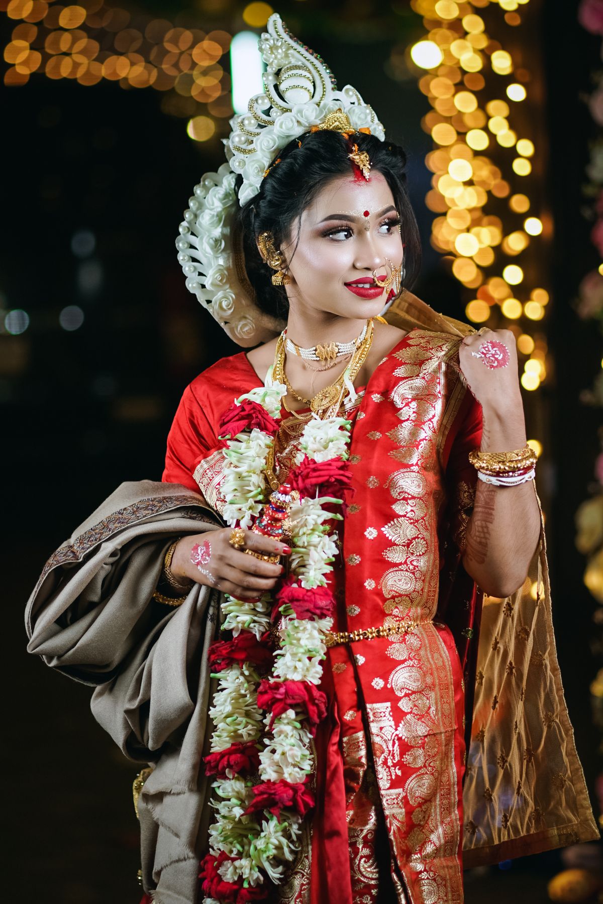Bride in a red silk saree with floral garlands and temple jewellery